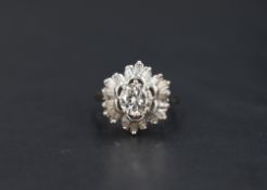 An open diamond cluster ring having a central brilliant cut diamond, approx 1ct within a frilled