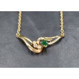 An 18ct gold necklace having a moulded central panel with diamond and emerald decoration on a