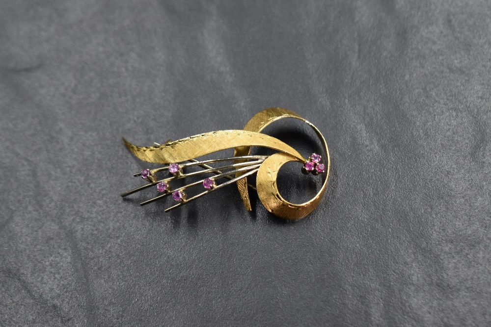 An 18ct gold spray design brooch, having a ribbon motif set with eight round cut rubies, approx 5.