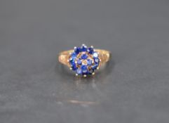 A blue gemstone set cluster ring, the central four stones with a twelve stone surround having