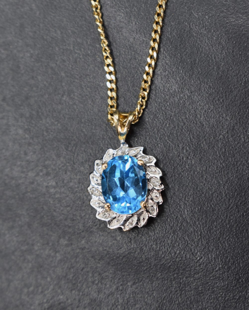 A blue gemstone (possibly blue topaz) and diamond 9ct gold cluster pendant, the oval cut blue