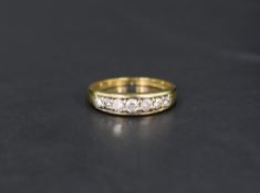 A diamond half eternity ring having seven diamonds in a channel setting on an 18ct gold loop, size O