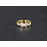 A diamond half eternity ring having seven diamonds in a channel setting on an 18ct gold loop, size O