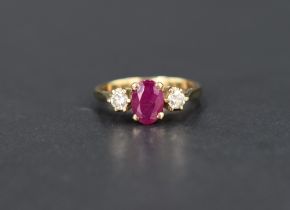 A ruby and diamond trilogy ring, the central oval cut ruby, approx 0.70ct, flanked by two