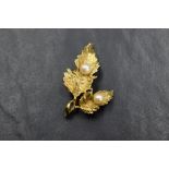 An 18ct gold brooch having a detailed double leaf design set with two cultured pearls, approx 6.3g