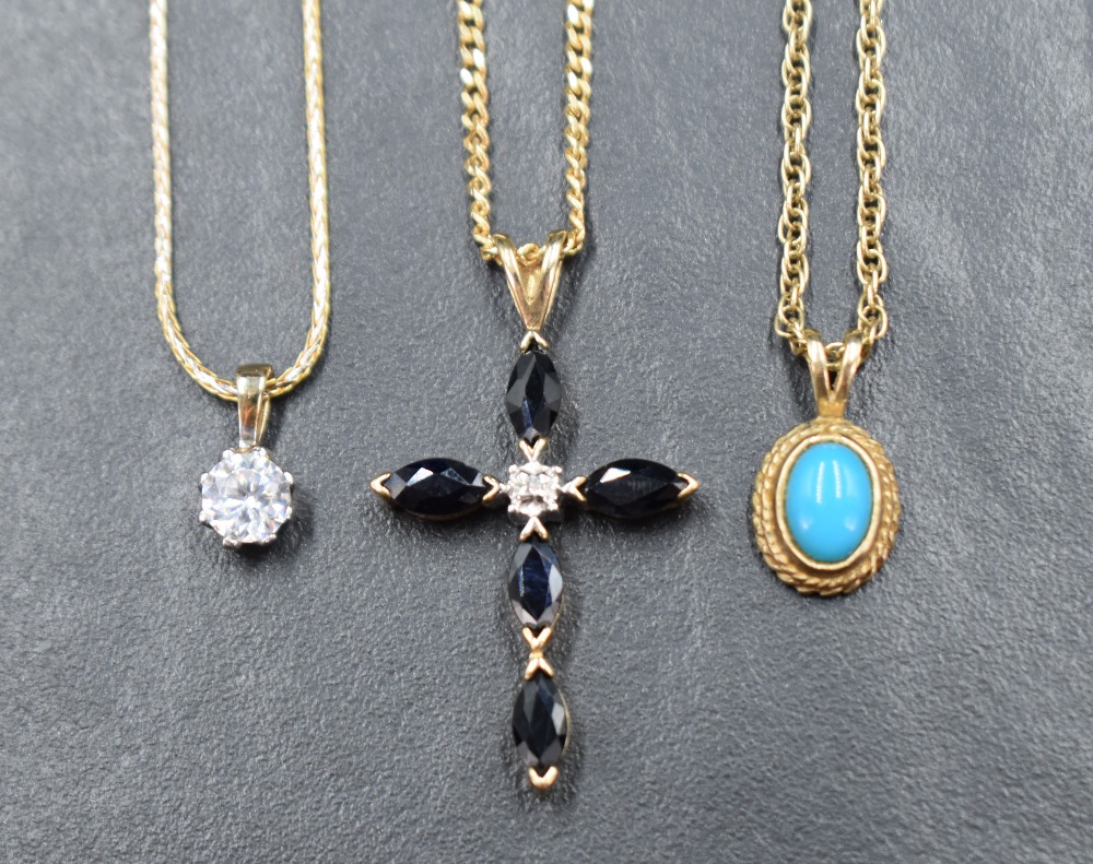 A collection of three pendants with chains comprising a 9ct gold sapphire and diamond cross on a 9ct