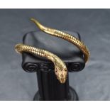 A 9ct gold flexible snake bangle, with ruby set eyes and decorative engraving to the head and