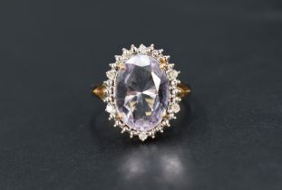 An amethyst and diamond cluster ring, the central oval cut amethyst measuring approximately 13.2 L x