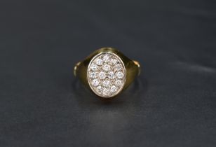 A gent's yellow metal signet ring having an oval panel set with 16 small diamonds total approx 0.