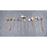 A collection of yellow metal stick pins including an enamel and diamond set horse shoe, a seed pearl