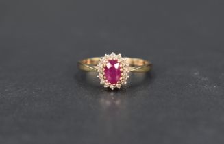 A ruby and diamond cluster ring, the central oval cut ruby, approx 0.60ct, with a sixteen diamond