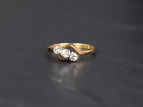 A diamond trilogy ring, approx 0.195ct total having twist shoulders to yellow metal loop, marks