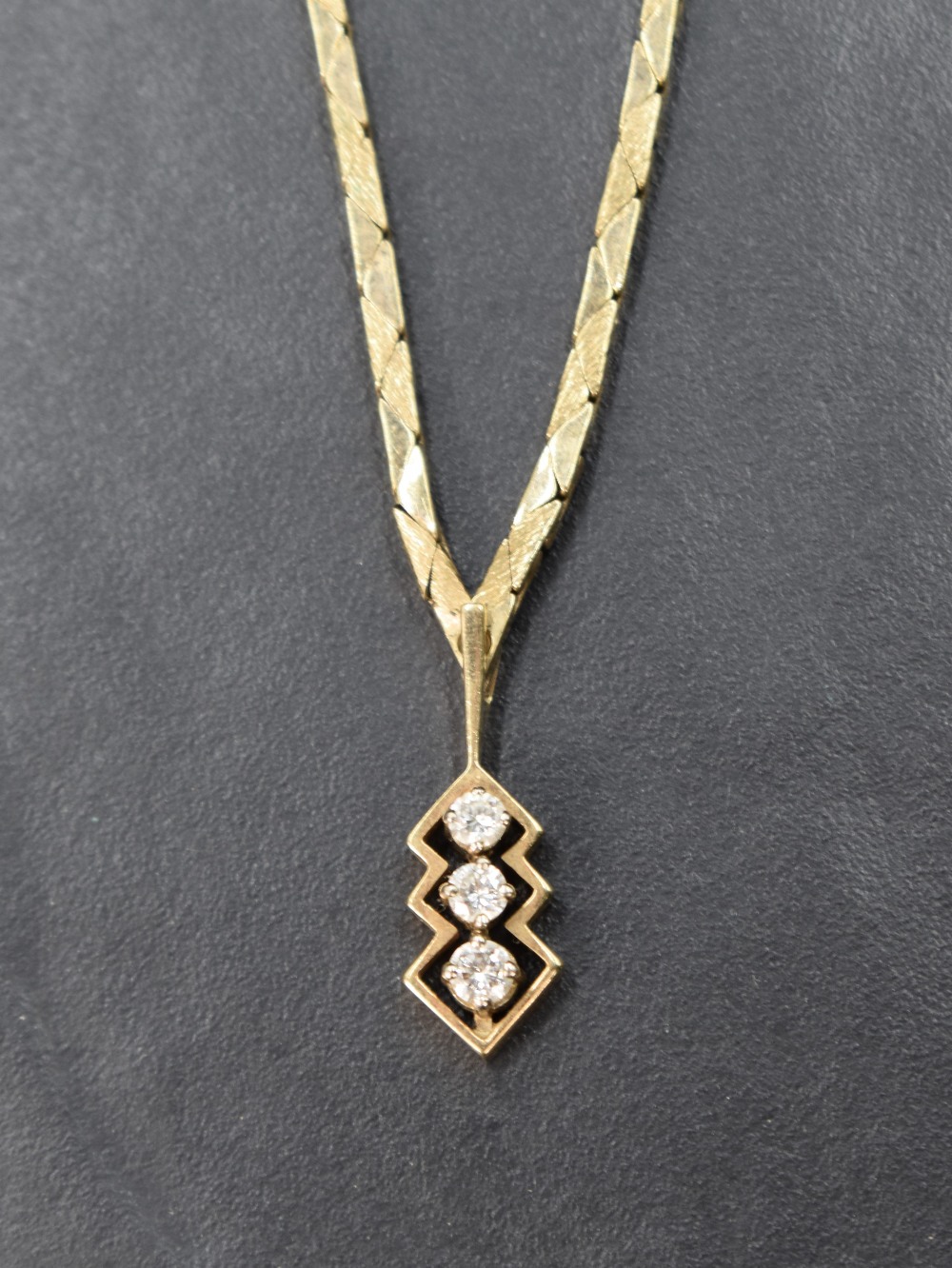 A 9ct gold necklace having three stone diamond drop, total approx 0.192ct in an open mount, with