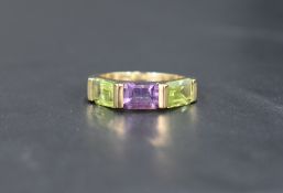 A 9ct gold band ring having a central amethyst flanked by two peridots, size N & approx 3.2g