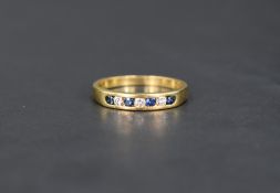 A sapphire and diamond half eternity ring having seven channel set stones on an 18ct gold loop, size