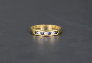 A sapphire and diamond half eternity ring having seven channel set stones on an 18ct gold loop, size