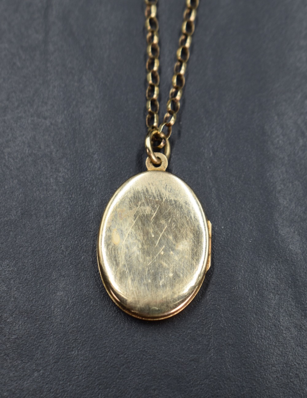 A yellow metal oval locket having a decorative floral design engraving on a 9ct gold rolo chain, 7. - Bild 2 aus 3