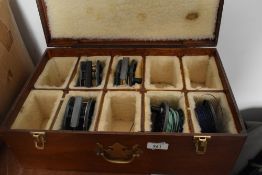 A wooden box, compartmentalised and lined containing a selection of fly fishing reels including