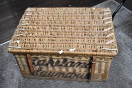 A large wicker laundry basket having Lakeland Laundries, Workington stencilled on back and front.