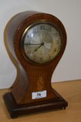 An Edwardian mahogany inlaid mantel clock, of balloon shape, raised on four brass metal feet,
