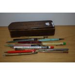 A 20th Century wooden sliding pencil box, measuring 21cm long, with vintage pens including a