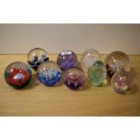 Nine assorted glass paperweights including Caithness and Selkirk glass etc.