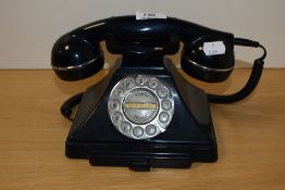 A vintage bakelite rotary dial telephone in black, measuring 15cm tall