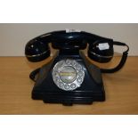 A vintage bakelite rotary dial telephone in black, measuring 15cm tall