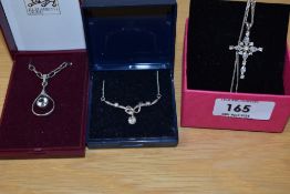 A collection of silver necklaces comprising a cubic zirconia set stylised cross, an open teardrop