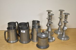 Six pewter engraved tankards, a lidded pewter jar and two pairs of metal candlesticks.