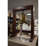 A large brass ships bell hanging from a substantial wooden frame.