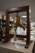 A large brass ships bell hanging from a substantial wooden frame.