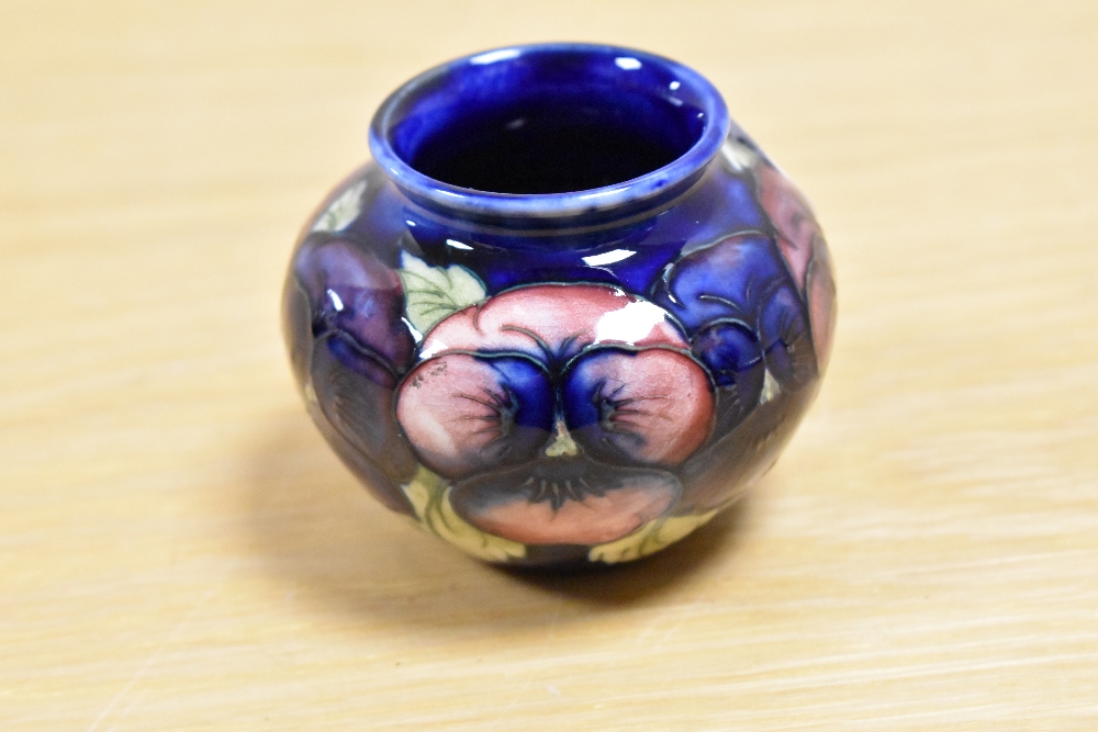 A William Moorcroft squat vase, in the Pansy pattern against a blue ground, measuring 6.5cm tall