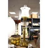 A brass oil lamp with corinthiun column base with cut glass reservoir and fluted etched shade and