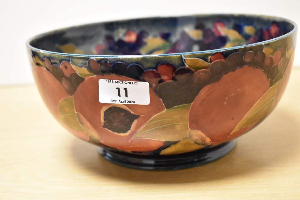 A Moorcroft Pottery fruit bowl, having tube lined grape and pomegranate design on cobalt blue