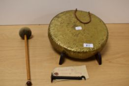 A brass dinner gong with hanger and beater.