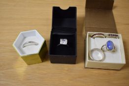 A collection of six silver rings comprising two bands, a cubic zirconia solitaire, a blue agate