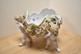 A Dresden porcelain figural centre-piece, formed as three three winged cherubs holding a flower