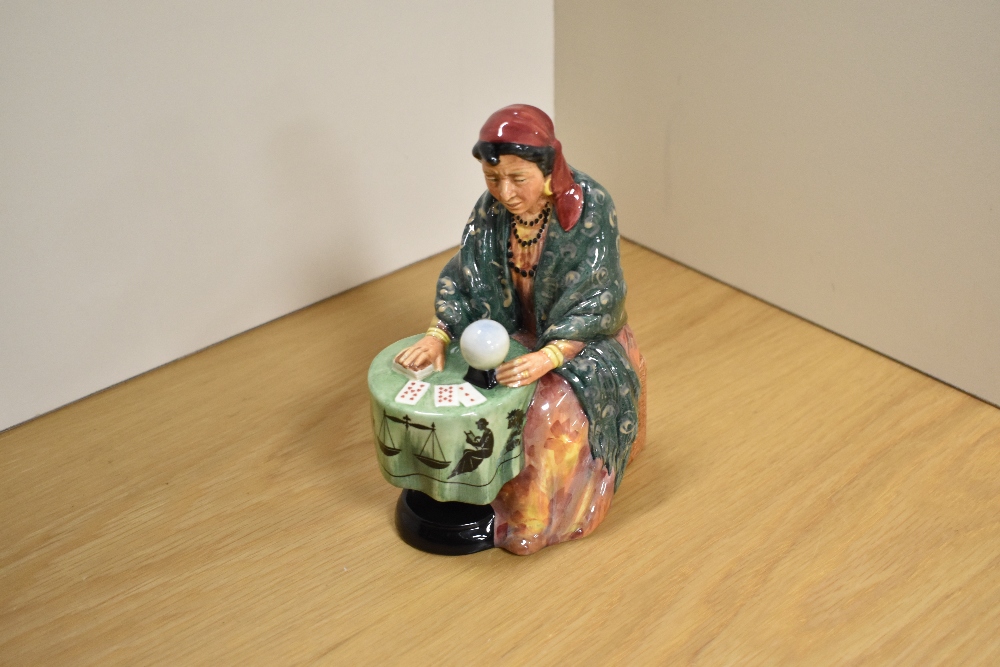 A Royal Doulton bone china figurine 'Fortune Teller' modelled seated at a table with crystal ball