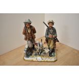 A CapoDiMonte Porcelain game hunting figure group, two hunters walking and their gun dog companion