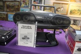 A Panasonic Bi Amp 4 Drive cd ' Ghetto Blaster ' on stand with remote and booklet - front of cd