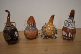 A group of four African gourde musical instruments, each decorated with traditional designs.