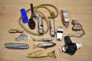 A collection of vintage whistles, including an EMCA City Whistle, pocket knives, and other items