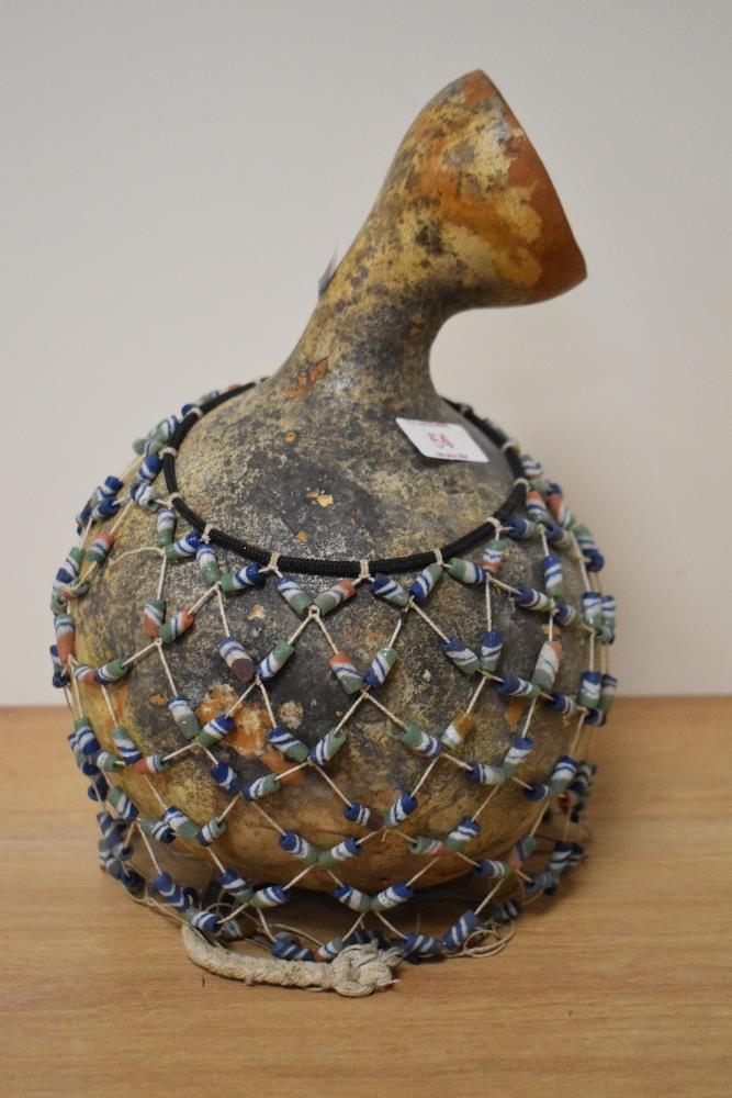An African gourde vessel with beaded netting.