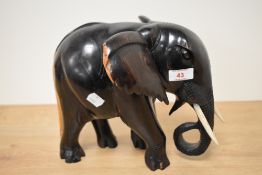 A 20th century African carved lignum vitae elephant with simulated ivory tusks, approx 23cm high.