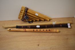 A trio of bamboo wind instruments including a set of pan pipes and two recorders and a bagpipe