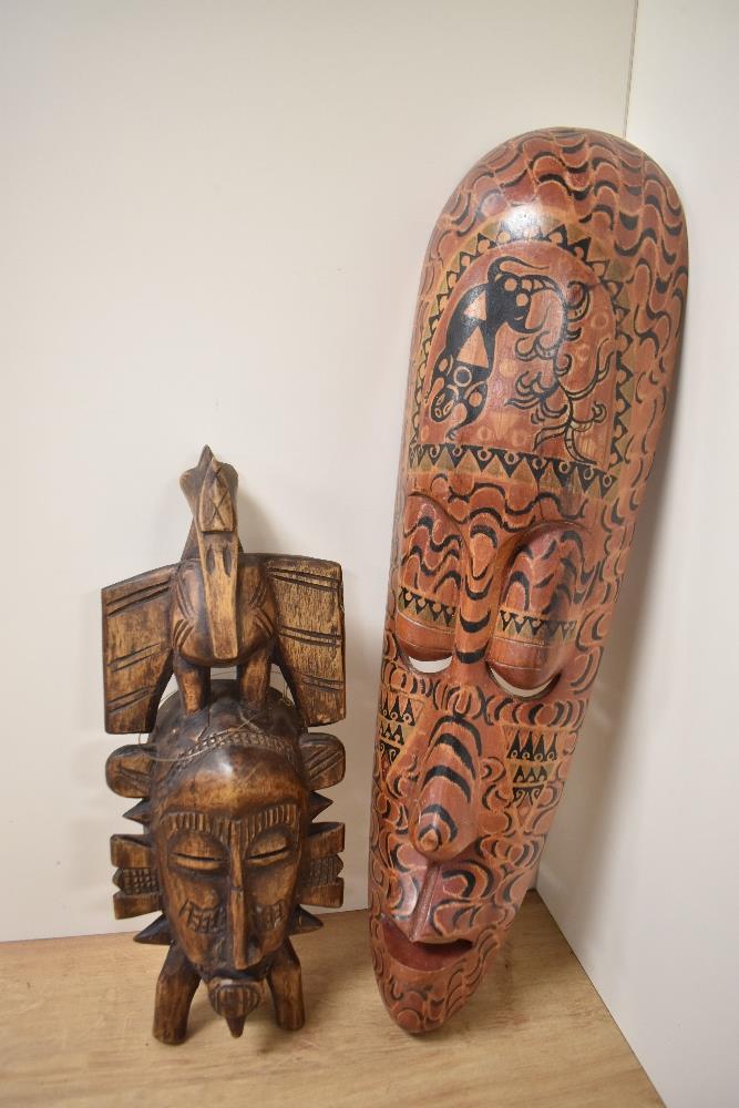 An Indonesian painted wooden tribal mask, of elongated form, measuring 48cm long, and another carved