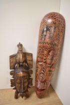 An Indonesian painted wooden tribal mask, of elongated form, measuring 48cm long, and another carved