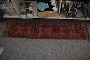 A traditional wool floor runner, having fringing to edges, in red and black hues.