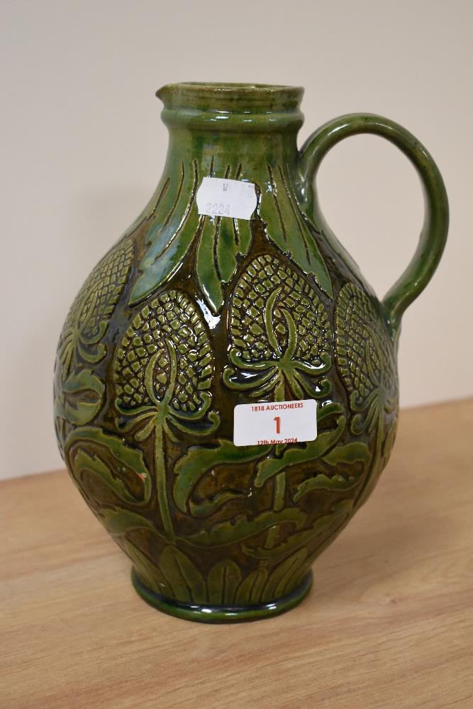 A Farnham Pottery flagon, having iridescent green glaze and abstract teasel pattern.